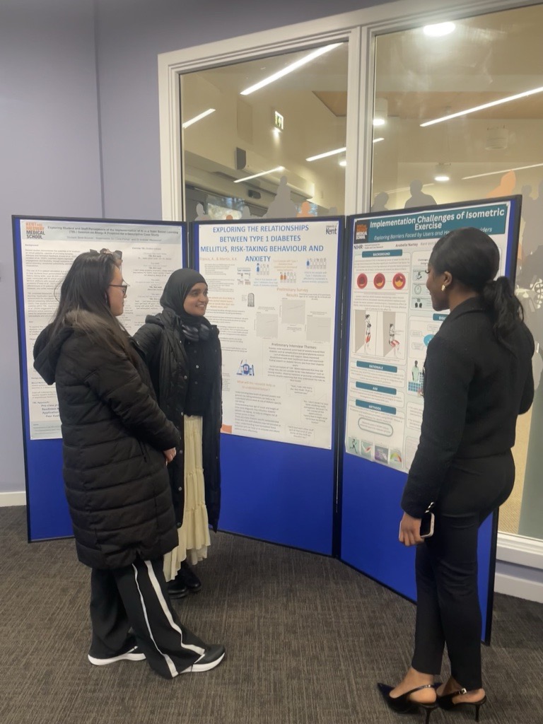 A KMMS student stood in front of a poster, presenting to guests